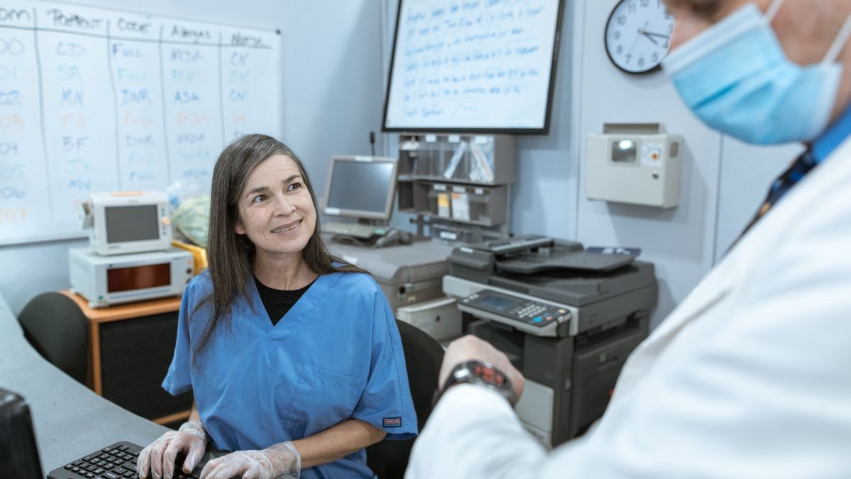 A charge nurse and physician collaborating at a hospital nurse station